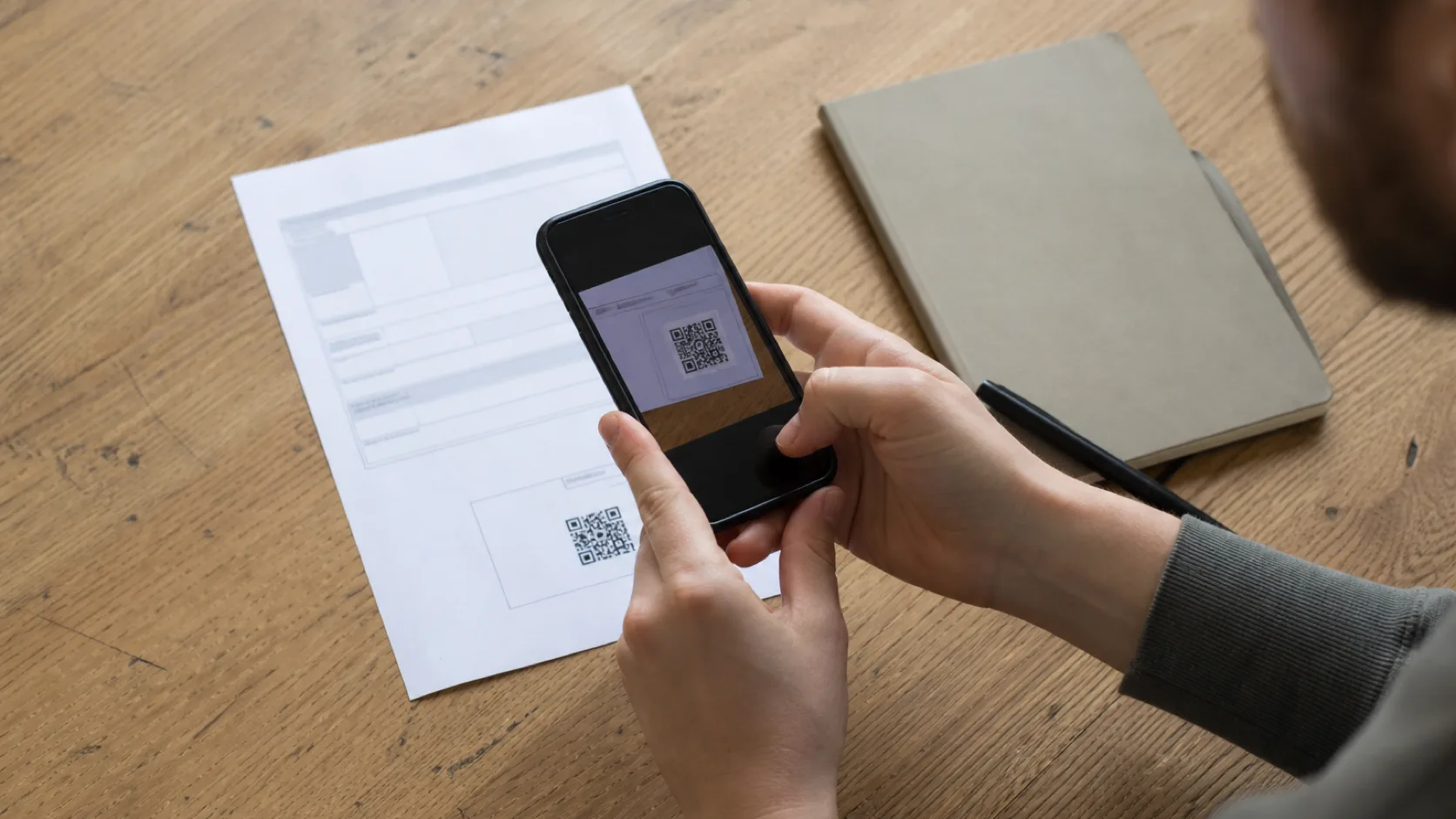 Podnikatel skenuje mobilem platební QR kód z vytištěné faktury